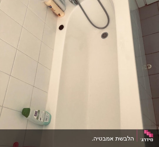 אמבטיה עם בקבוקי שמפו וסבון על הרצפה